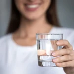 A woman holding a glass of water