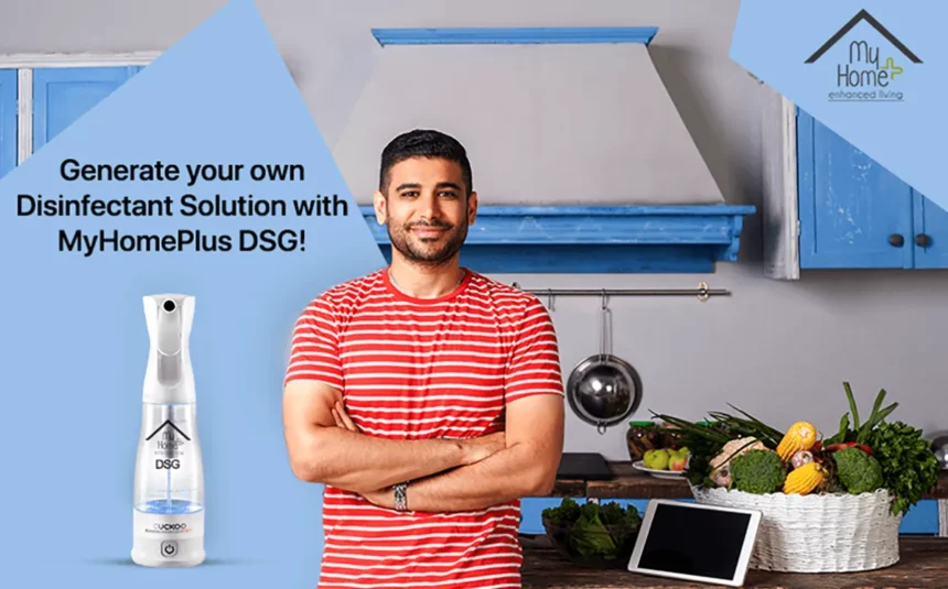 A young Indian man standing in the kitchen with MyHomePlus DSG disinfectant solution spray in the frame.