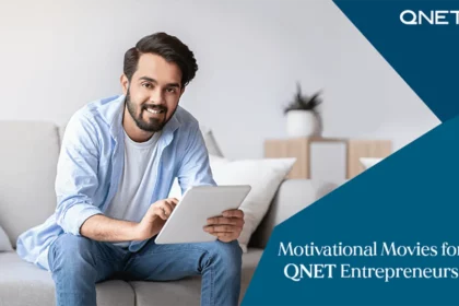 A young QNET entrepreneur smiling while watching motivational movies on his tablet in an indoor setting