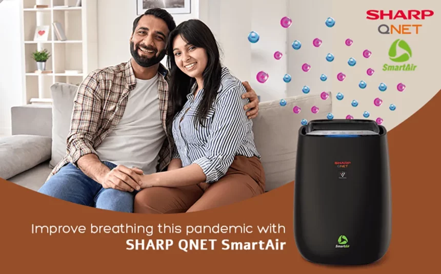 A young couple sitting on the couch with SHARP QNET SmartAir air purifier in the frame