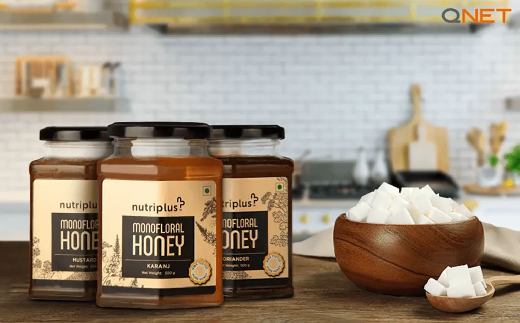 A tabletop featuring Nutriplus Monofloral Honey next to a bowl of sugar cubes