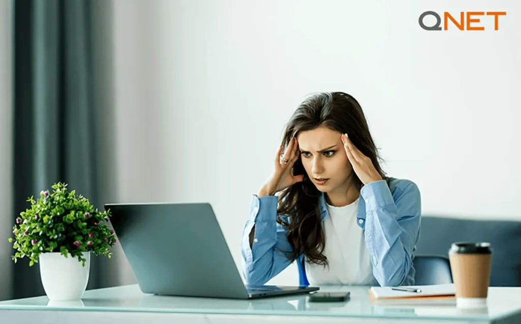 A stressed young woman holding her head | QNET India 