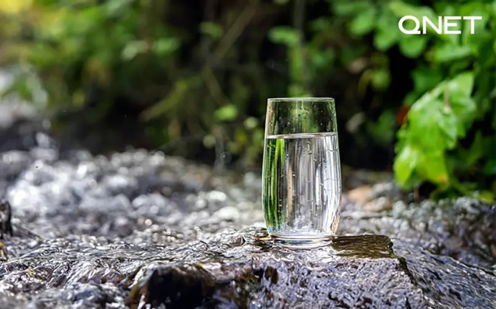 A glass of water kept at a natural location over flowing water