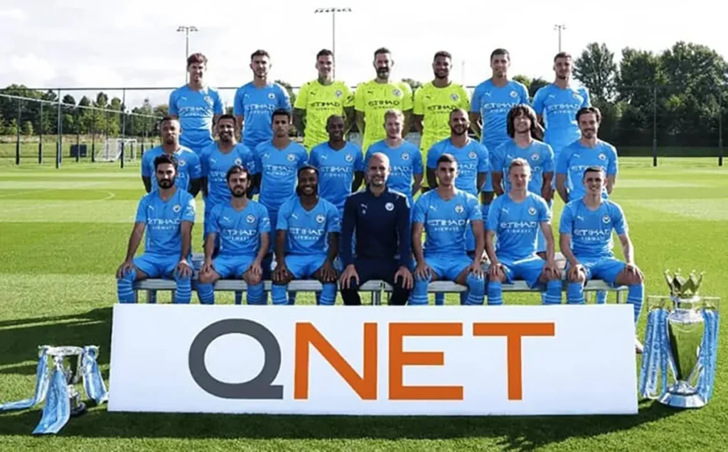 ManCity players group picture with a QNET banner