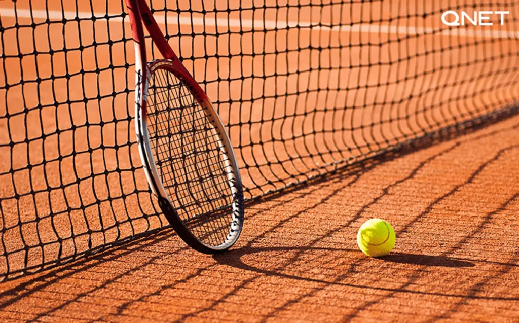 Tennis racket and a ball on a clay court