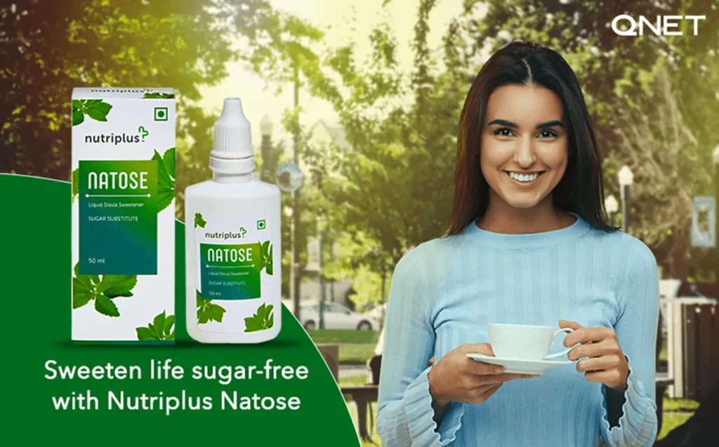 A happy woman drinking coffee in the park with Nutriplus Natose by QNET in the frame