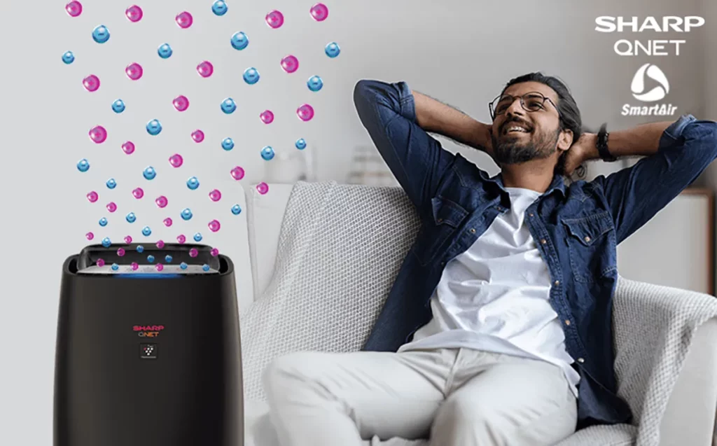A young Indian man relaxing on the couch with SHARP QNET SmartAir air purifier in the frame
