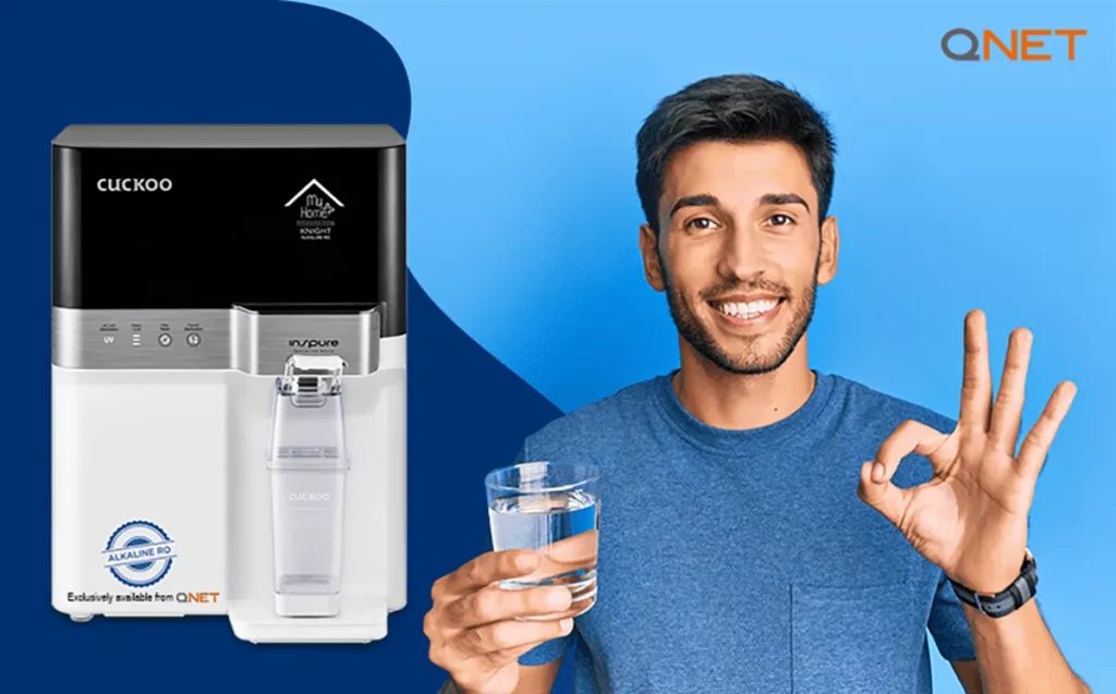A young Indian man standing with a glass of water with MyHomePlus KNIGHT – Alkaline RO Water purifier in the frame