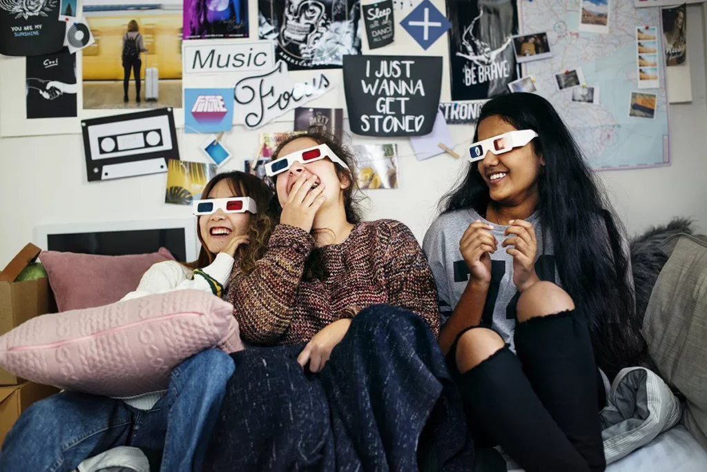 Friendship Day 2019: Three girls laughing while watching a movie with 3D glasses at home
