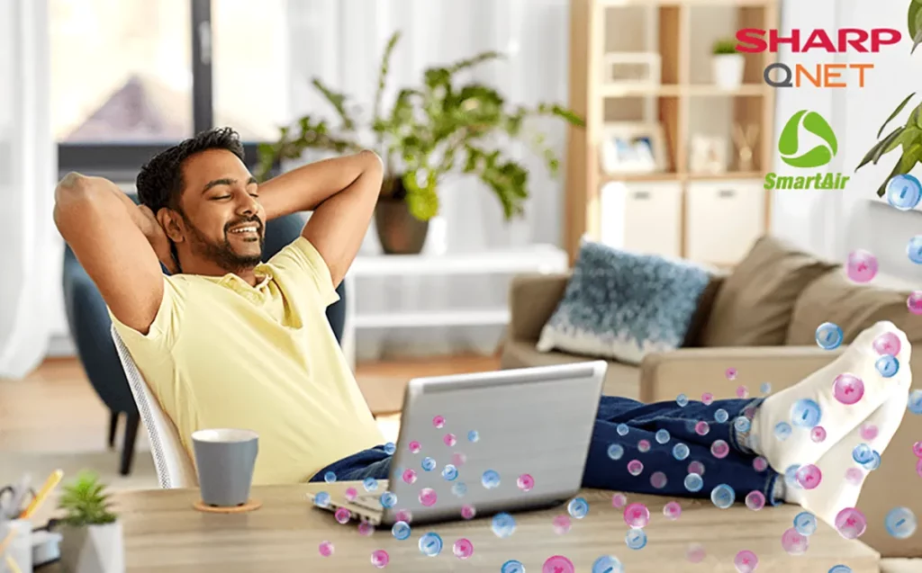 Indian man with a smile breathing fresh air while working from home with SHARP QNET SmartAir air purifier.