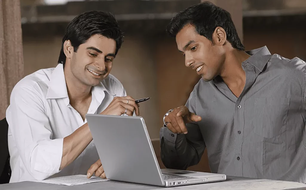 Two young men looking at the laptop screen and having a conversation.