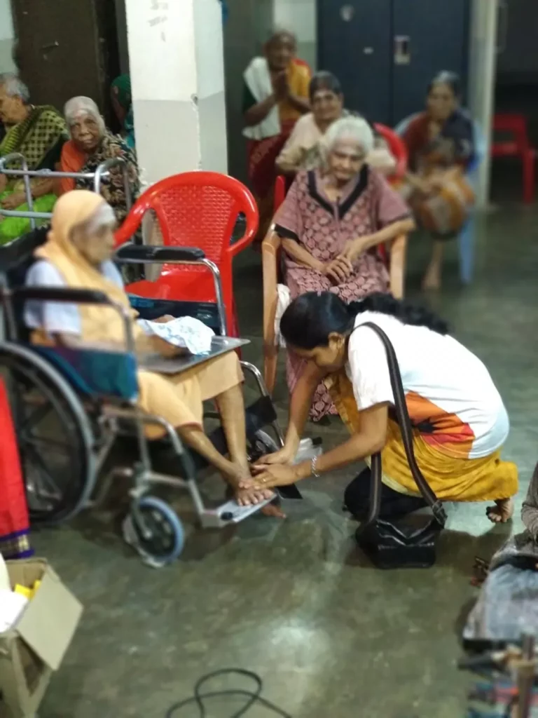 QNET Independent representative touching the feet of old woman