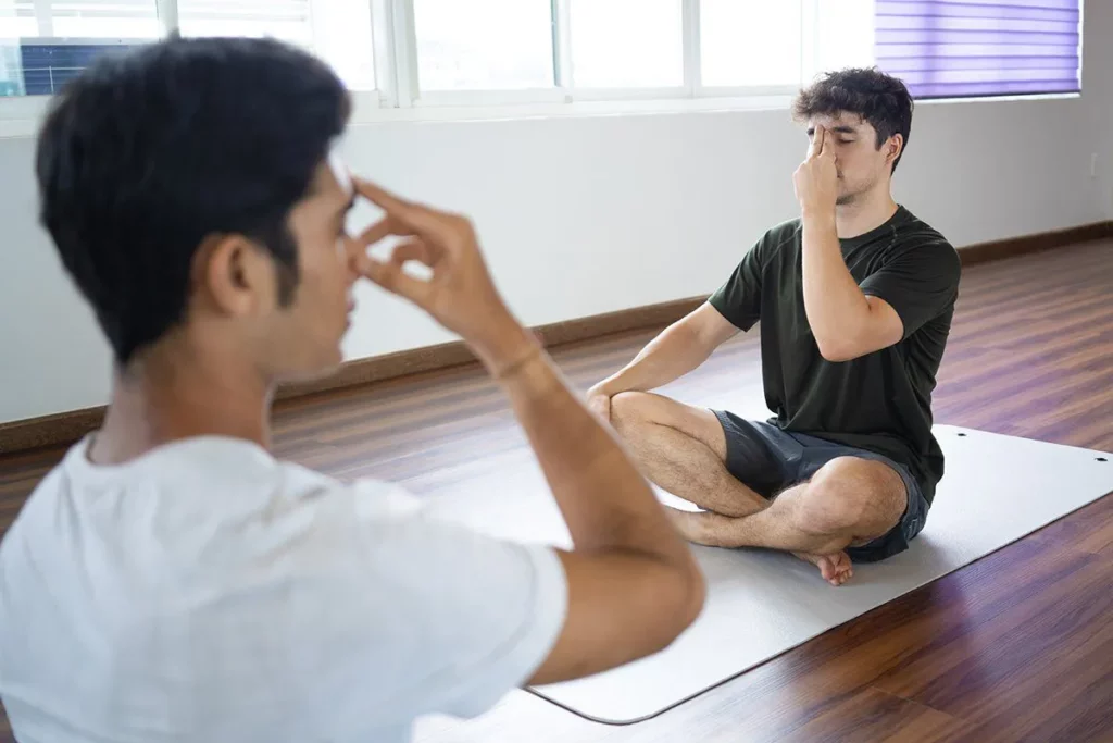 International Day of Yoga : two young men performing breathing exercise.