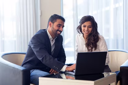 man and woman sitting at computer smiling working